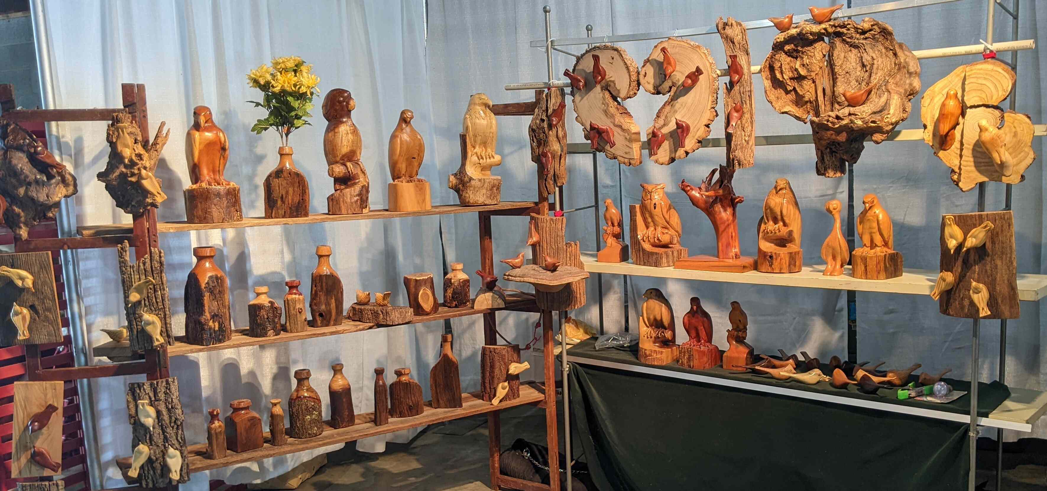 photograph of a display of stylized wood carvings of various birds, dry vases and wall hangings by gary carver of carverscarvings