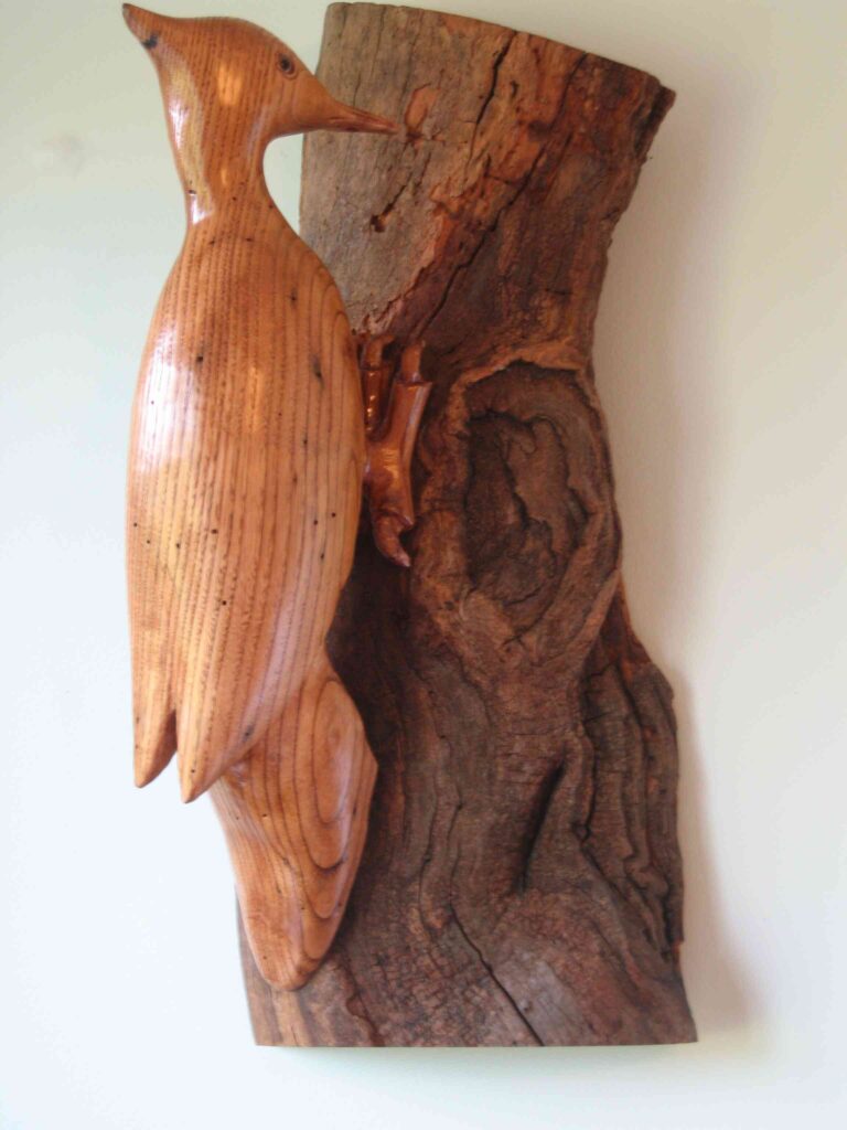 stylized american chestnut wood carving of a pileated woodpecker mounted on a branch of chestnut by gary carver of carverscarvings