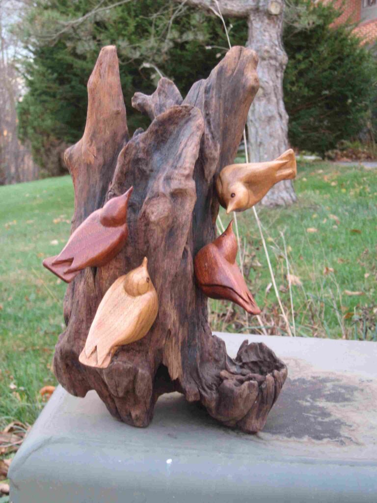 four stylized wood carvings of nuthatches on drift wood display