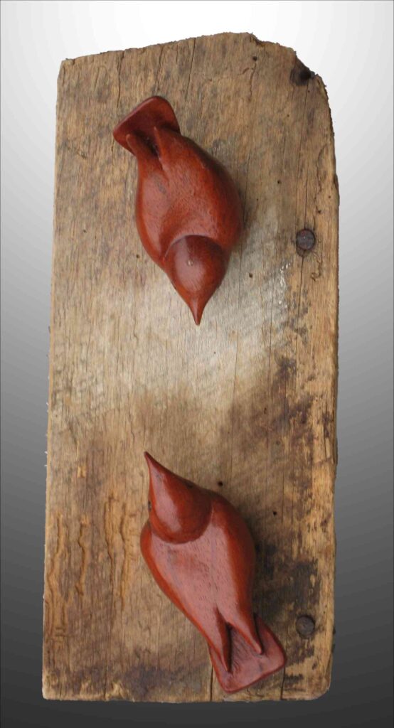 two stylized wood carvings of nuthatch birds mounted on an old barn board by gary carver of carverscarvings