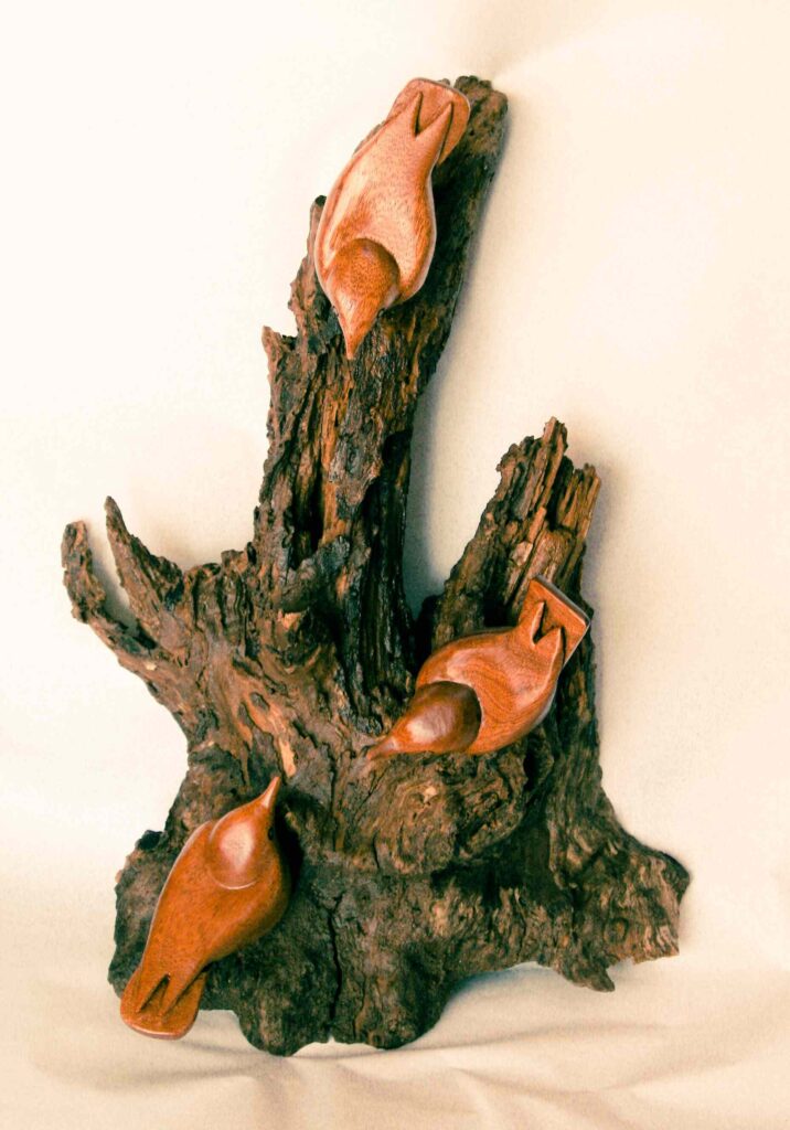 three stylized wood carvings of nuthatch birds mounted on a chestnut tree root by gary carver of carverscarvings