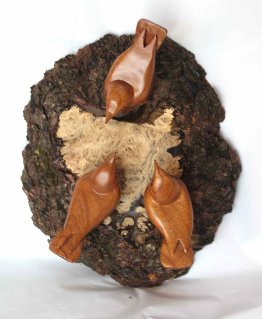 three stylized chestnut wood carvings of nuthatches mounted on a burl by gary carver of carverscarvings