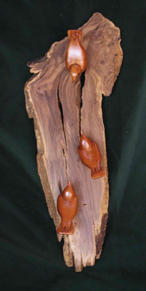 three stylized wood carvings of nuthatches mounted on an oak root slab by gary carver of carverscarvings