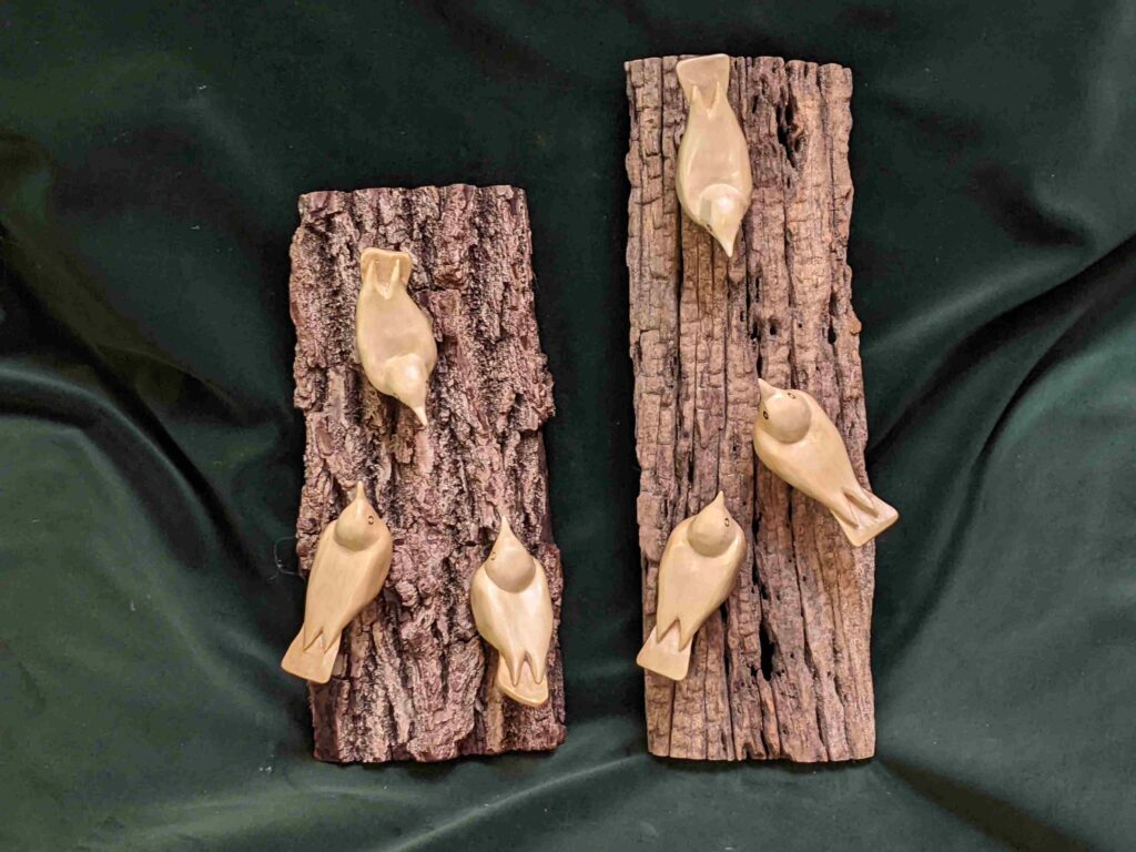 two separate wall hangings each with three stylized wood carvings of nuthatches by gary carver of carverscarvings