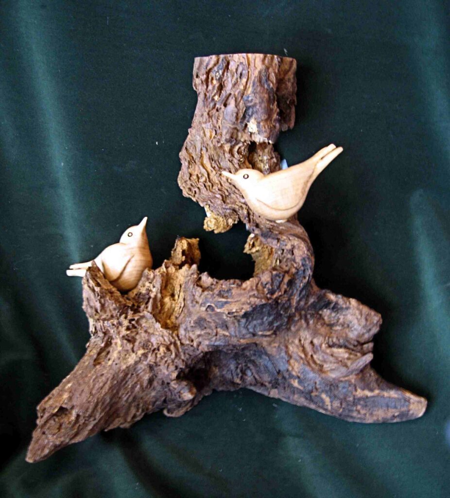 two stylized wood carvings of nuthatches on a tree root display by gary carver of carverscarvings