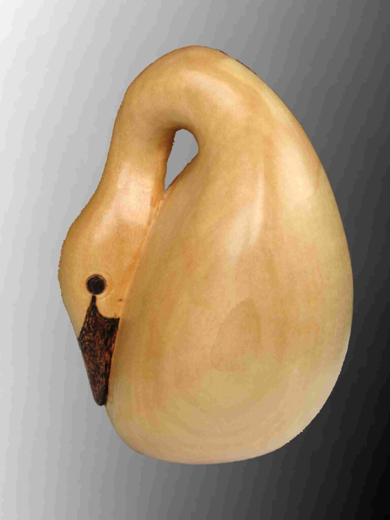 photograph of the side view of a stylized wood carving of an egg shaped baby swan by gary carver of carverscarvings