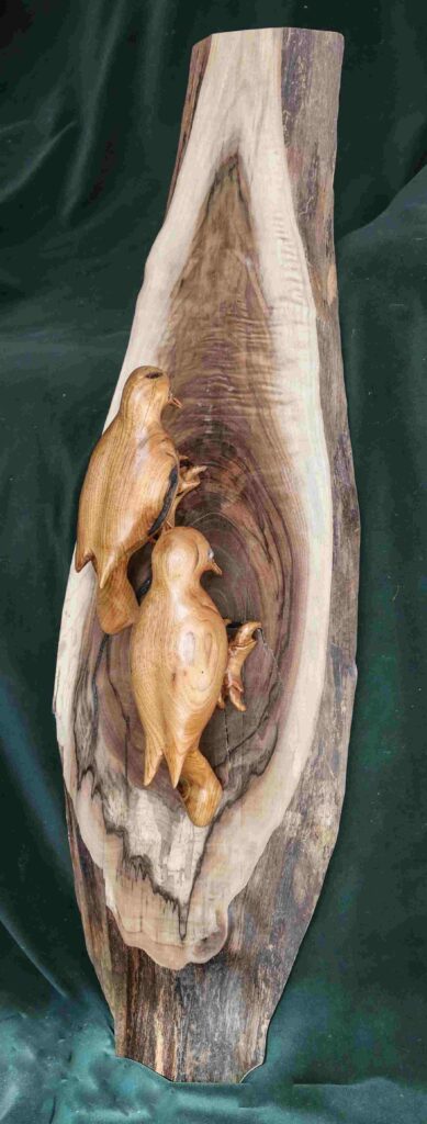 stylized wood carvings of two woodpeckers on a slab by gary carver of carverscarvings